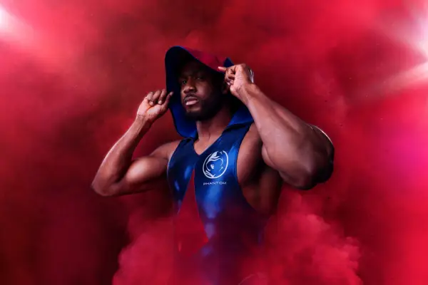 Phantom holding a hood over his head with red smoke surrounding him.