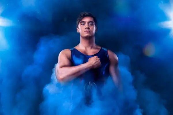 Apollo AKA Alex Gray stood with his fist to his chest surrounded by blue smoke