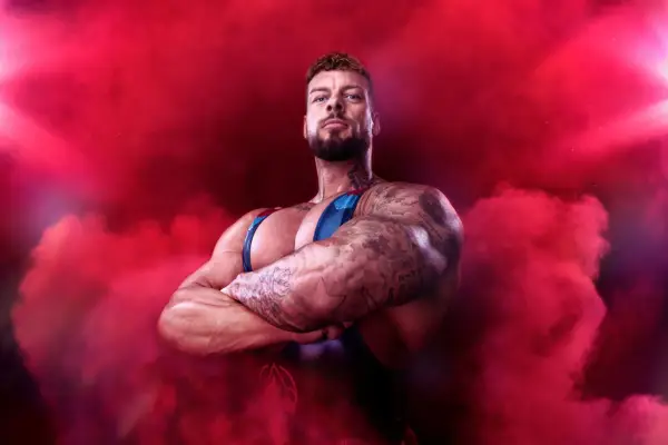 Giant, Gladiators. He is surrounded by red smoke with his arms crossed and is looking downwards.