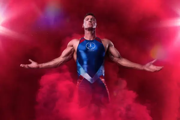 Legend stood with his arms spread on either side with red smoke around him