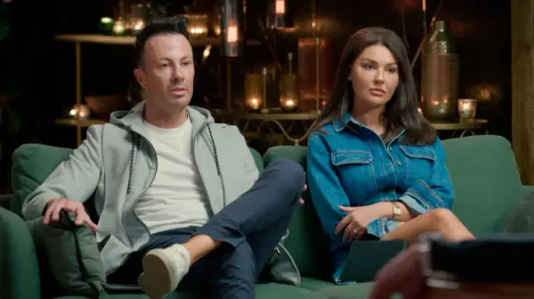 Lauren and Clint sat down on a green sofa, looking unimpressed.