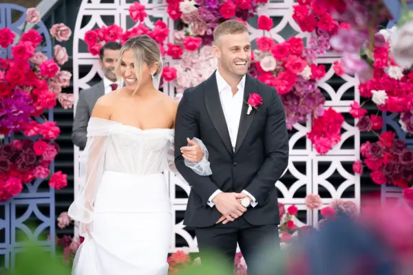 Married at First Sight Australia season 11 couple Sara and Tim smiling and linking arms on their wedding day.