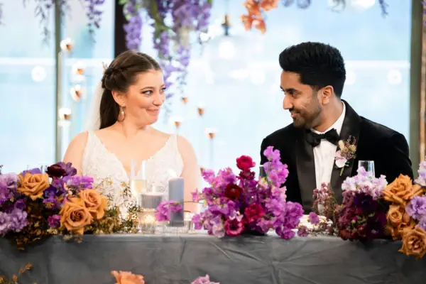 Married at First Sight Australia season 11 couple Natalie and Collins smiling at each other as they sit at the head table during their wedding reception.