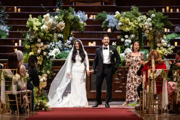 A bride and groom stood next to each other, holding hands and smiling.