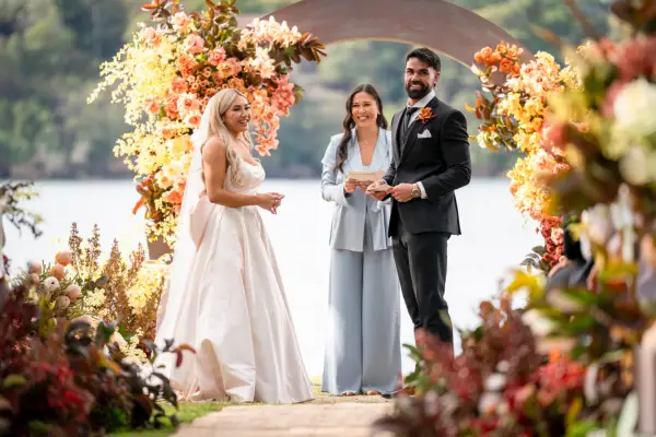 Awhina and Adrian in a wedding dress and tuxedo, stood opposite each other and smiling.
