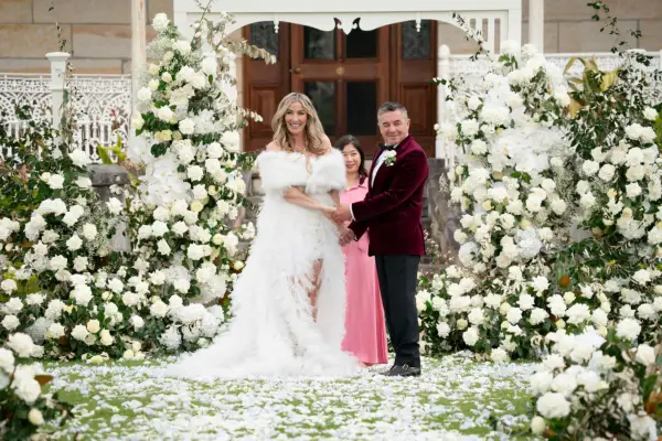 Morena and Tony holding hands and smiling as they turn to a crowd.