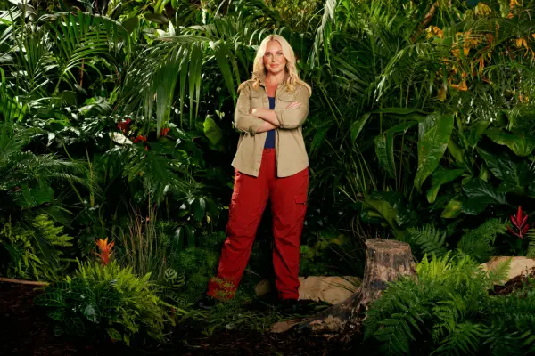 Josie Gibson wearing a khaki shirt and red trousers while posing in front of some bushes ahead of I
