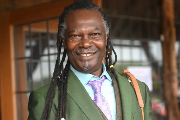 Levi Roots smiling at the camera and wearing a green suit and purple tie