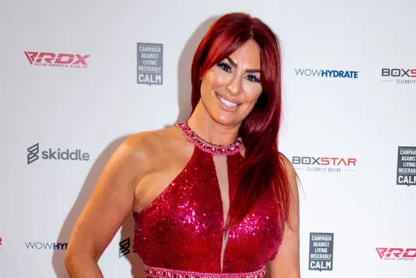 Lauren Simon in a red sequin dress with her hands to her side. She is smiling ahead