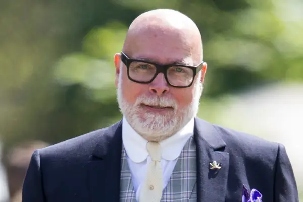 Gary Goldsmith facing ahead, wearing a suit and glasses. He is bald and has a white coloured beard