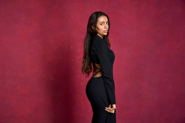 A woman wearing a black dress, turned to the side.