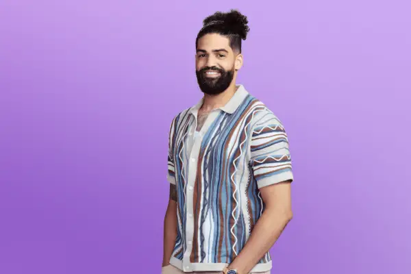 Ariel in a patterned polo shirt posing in front of a purple background