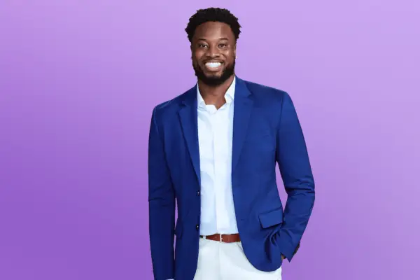 Deion wearing a blue blazer and white shirt with his hand on his pocket.