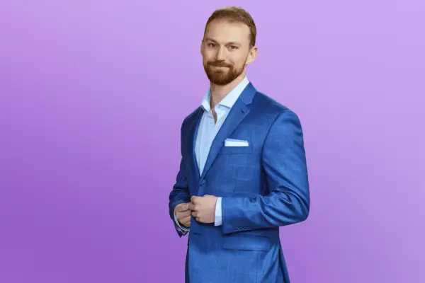 Ben in a blue suit posing in front of a purple background