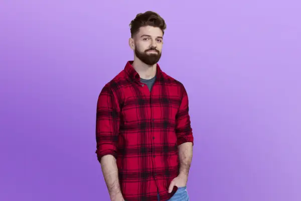 Laura is in a dark green dress posing in front of a purple background