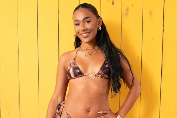 Jess Spencer posing for a photo in a bikini, with one hand on her hip as she smiles ahead.