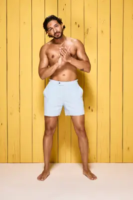 Munveer Jabal poses in shorts against a wooden yellow wall for Love Island 2024.