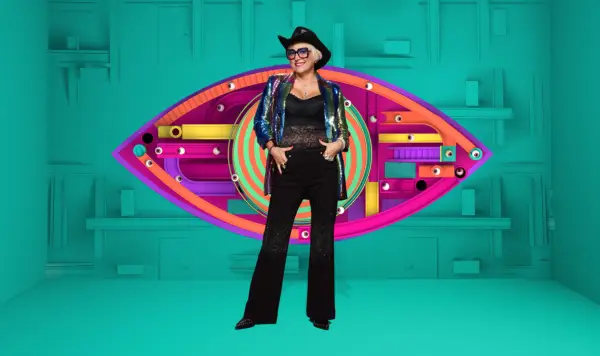 Caroline wearing a black mesh top and black flares paired with a black cowboy hat, smiling ahead.