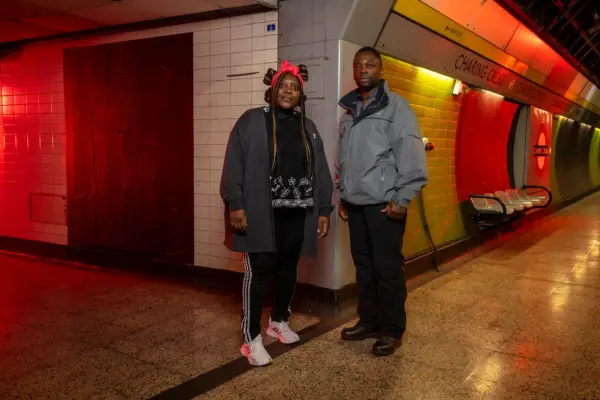 Christine and Munya stood in exercise clothing in a dimly lit Charing Cross station. They are stood next to each other while looking ahead