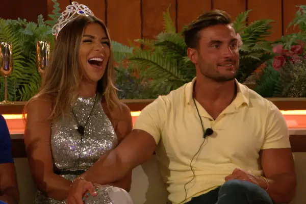 Ekin-Su and Davide on Love Island 2022. Ekin-Su is in a silver dress and a tiara as she laughs while Davide is holding her leg as he wears a yellow polo shirt