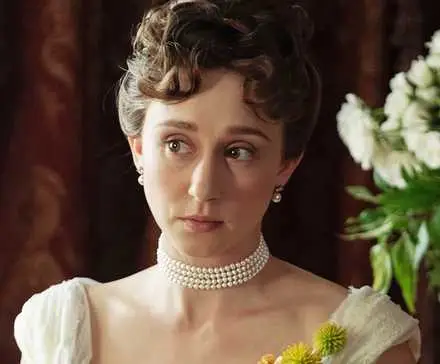 Taissa Farmiga as Gladys Russell looking off to the right next to a vase of flowers in The Gilded Age Season 3.