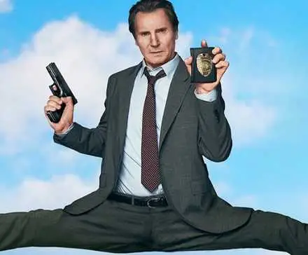 Liam Neeson as Frank Drebin Jr. in promotional image with legs spread across frame for The Naked Gun (2025).