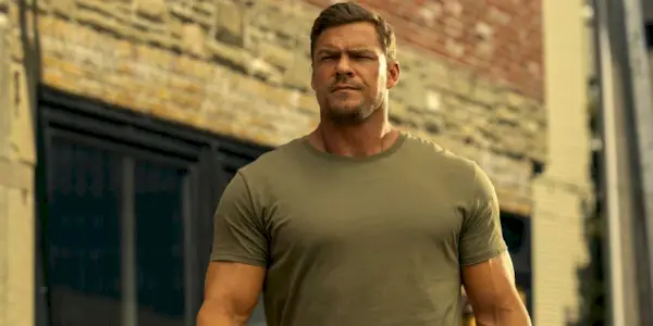 Alan Ritchson as Jack Reacher walking down the street outside in Season 3 of Reacher.