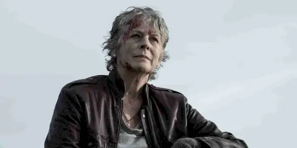 Melissa McBride as Carol wears a leather jacket and looks off camera