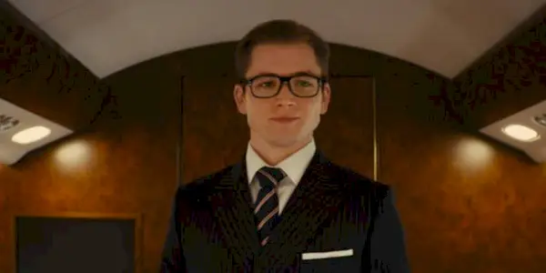 Eggsy, played by Taron Egerton, smiles in his new suit in 
