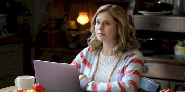 Sam (Rose McIver) sits at a table with her laptop in a scene from 