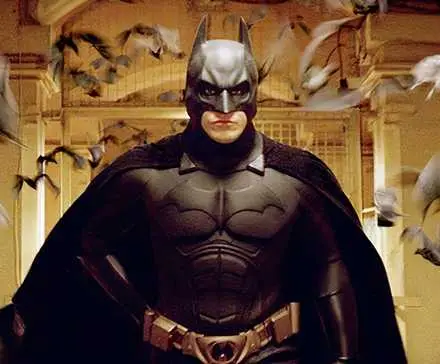Christian Bale as Batman surrounded by bats in Batman Begins.