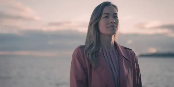 Yvonne Strahovski as Serena Joy, standing alone on a beach, in The Handmaid