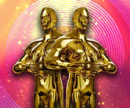 Two Oscars Statuettes against a bright pink and yellow background