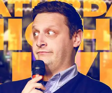 Tim Robinson holding a mic in front of the SNL logo