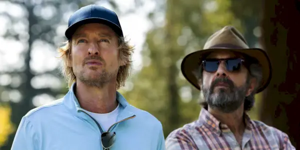 Owen Wilson as Pryce standing next to Marc Maron as Mitts outside on a golf course in Stick