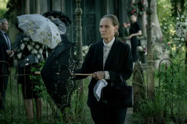 Beth Grant in Mayfair Witches wearing a black suit, holding an umbrella