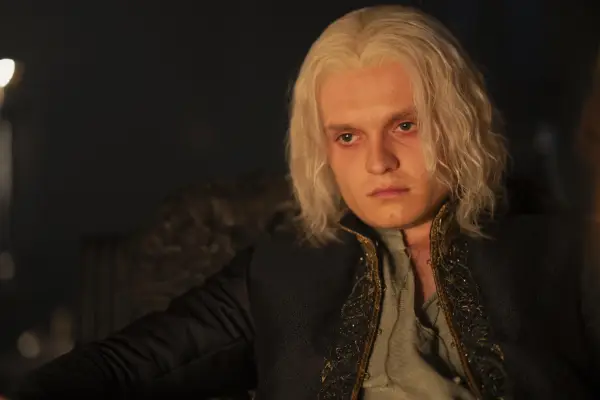 Tom Glynn-Carney sits by firelight as King Aegon II Targaryen in House of the Dragon season 2.