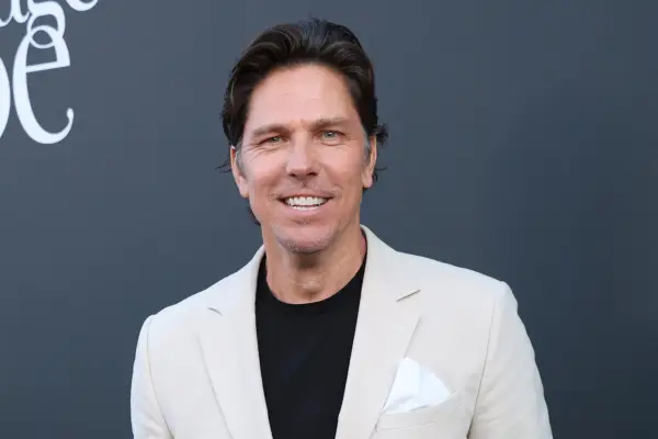 Michael Trucco wearing a black top and cream blazer