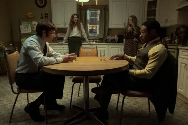 Malcolm Goodwin as young Dupin and Zach Gilford as young Roderick Usher in The Fall of the House of Usher sat around a table, with two female characters standing in the background