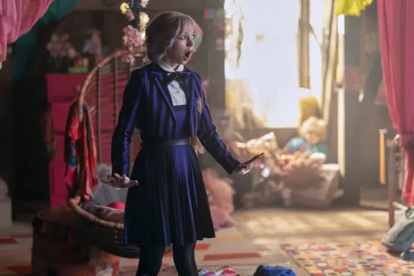 Emma Myers as Enid Sinclair in Wednesday season 2 dressed in her purple school uniform and looking shocked as she stands in the middle of her room.