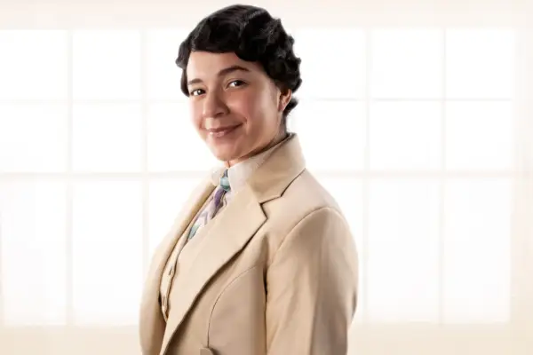 Quelin Sepulveda as Muriel in Good Omens season 2, wearing a brown suit