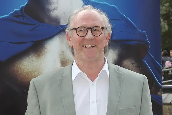 Peter Davison wearing a grey suit jacket and white shirt