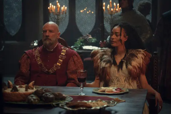 Cassie Clare and Graham McTavish in The Witcher sitting at a banquet table