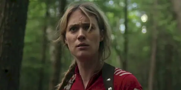Kirsten in the woods looking intently ahead in Station Eleven