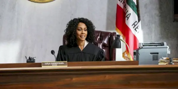 Simone Missick as Judge Lola Carmichael sits at the bench in a courtroom with a flag behind in All Rise.