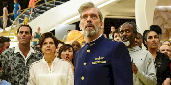 Hugh Laurie as Ryan Clark looking up with a surprised expression while a group of passengers stand behind him in Avenue 5
