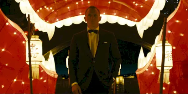 Bond stands in a tuxedo against chinese decorations and lanterns
