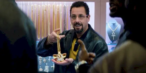 Adam Sandler holding a gold necklace in 