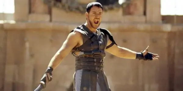 Maximus yelling and spreading his arms while holding a sword in Gladiator