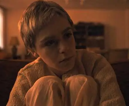 Kiernan Shipka as Carrie Anne Camera hugging her legs, looking worried in Longlegs